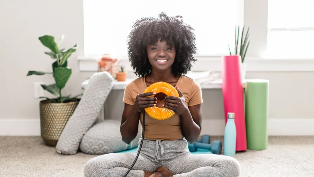 Person holding an AmpCoil electromagnetic coil while preparing for a wellness session.